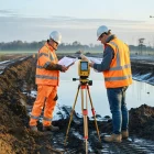 Engineers survey a misty British development site at sunrise