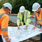 Civil engineering team coordinates surveys and site preparation near an urban road