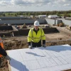 Engineer and site manager review plans beside active earthworks machinery