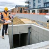 Drainage inspection team examining an open concrete manhole chamber on site